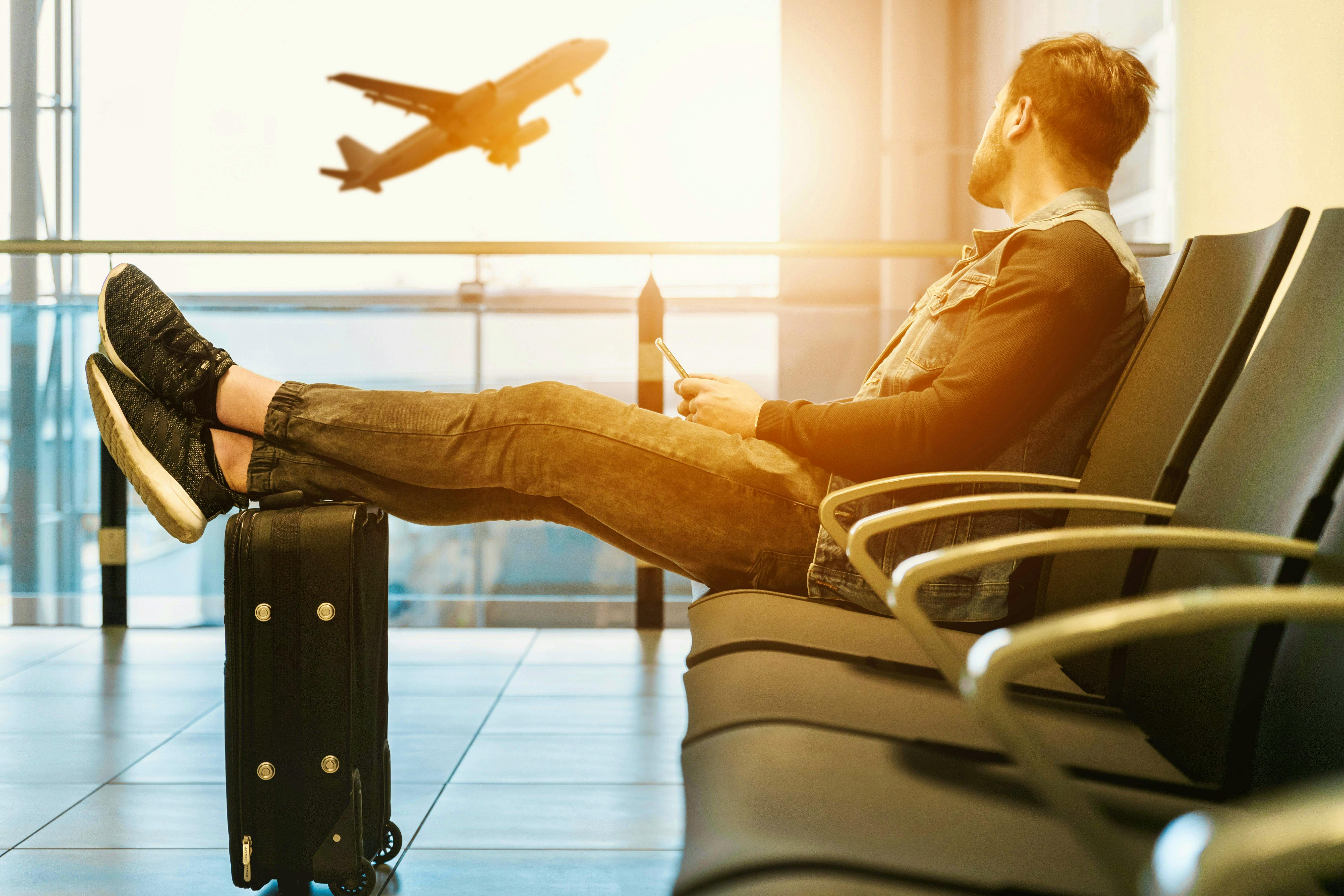 Man sitting on gang chair with feet on luggage looking at airplane photo – Free Travel Image on Unsplash Jeshoots-com-mSESwdMZr-
