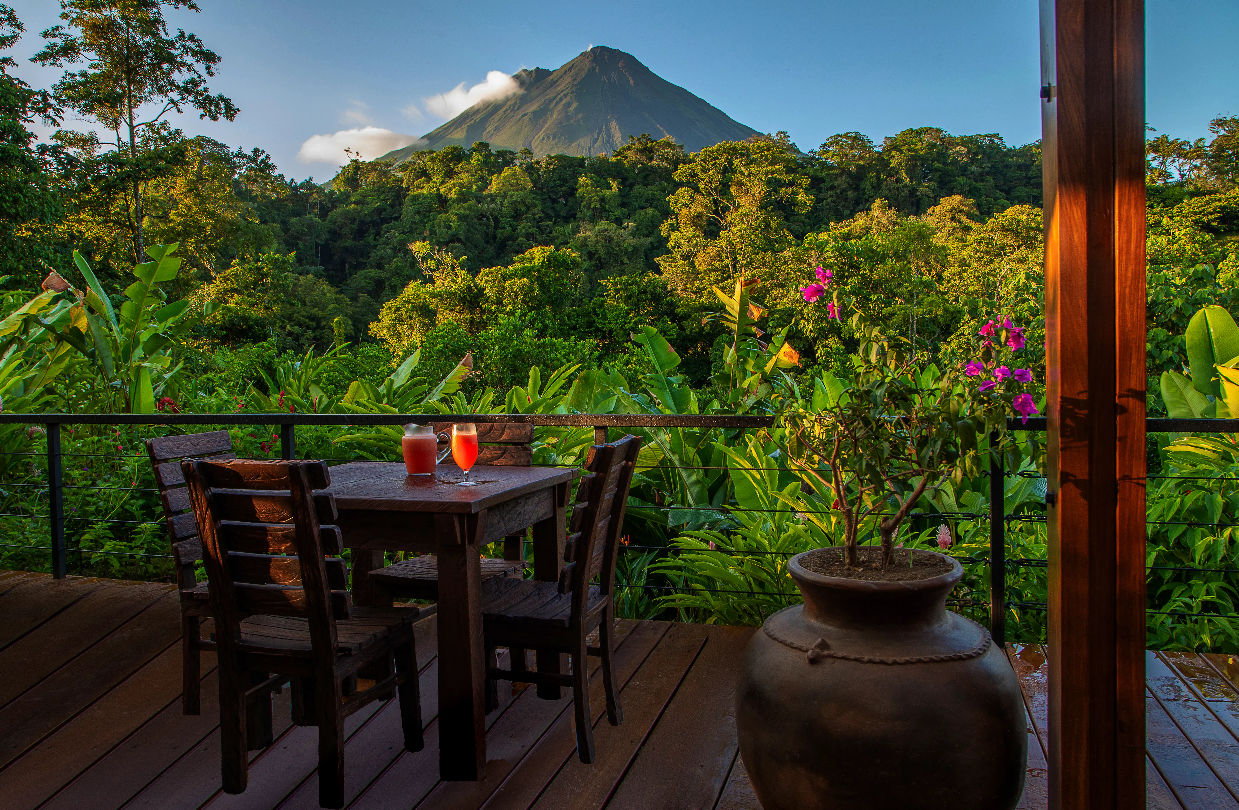 Balcony table with fruit drinks at Amor Arenal, overlooking rainforest and Arenal volcano in Costa Rica