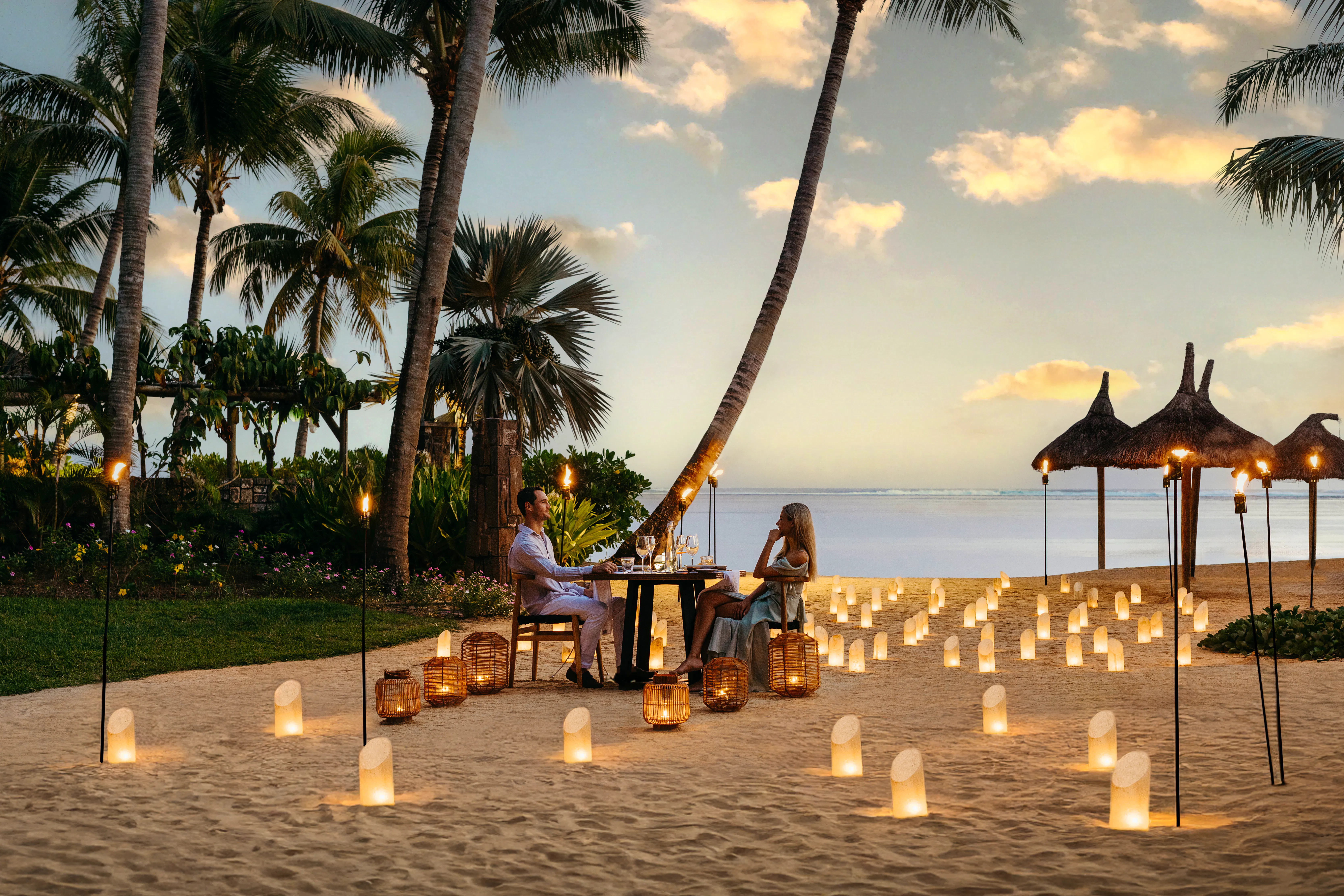 Couple having a candlelit dinner on the beach at Heritage Le Telfair in Mauritius at sunset