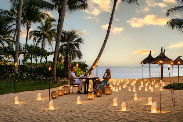 Couple having a candlelit dinner on the beach at Heritage Le Telfair in Mauritius at sunset
